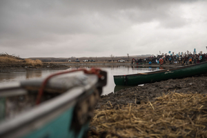 Water protectors at Standing Rock wait along the right bank of the river to peacefully travel across to say communal prayers Thanksgiving Day.