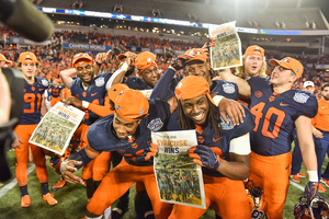 Syracuse players hold up copies of The Daily Orange after SU's Camping World Bowl win.