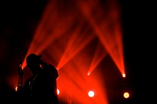 Big Sean silhouetted by his stage set while he performs.