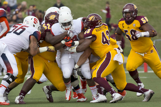 Senior Adonis Ameen-Moore protects the ball while a gang tackle attempts to bring him down.