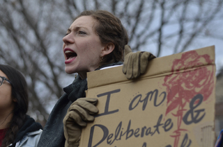 Terese Gagnon shows her agreement with the speaker and also holds a sign showing her support for the rally's efforts.