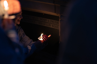 Remembrance Scholar Corey Henry holds her candle up to the Remembrance Wall.